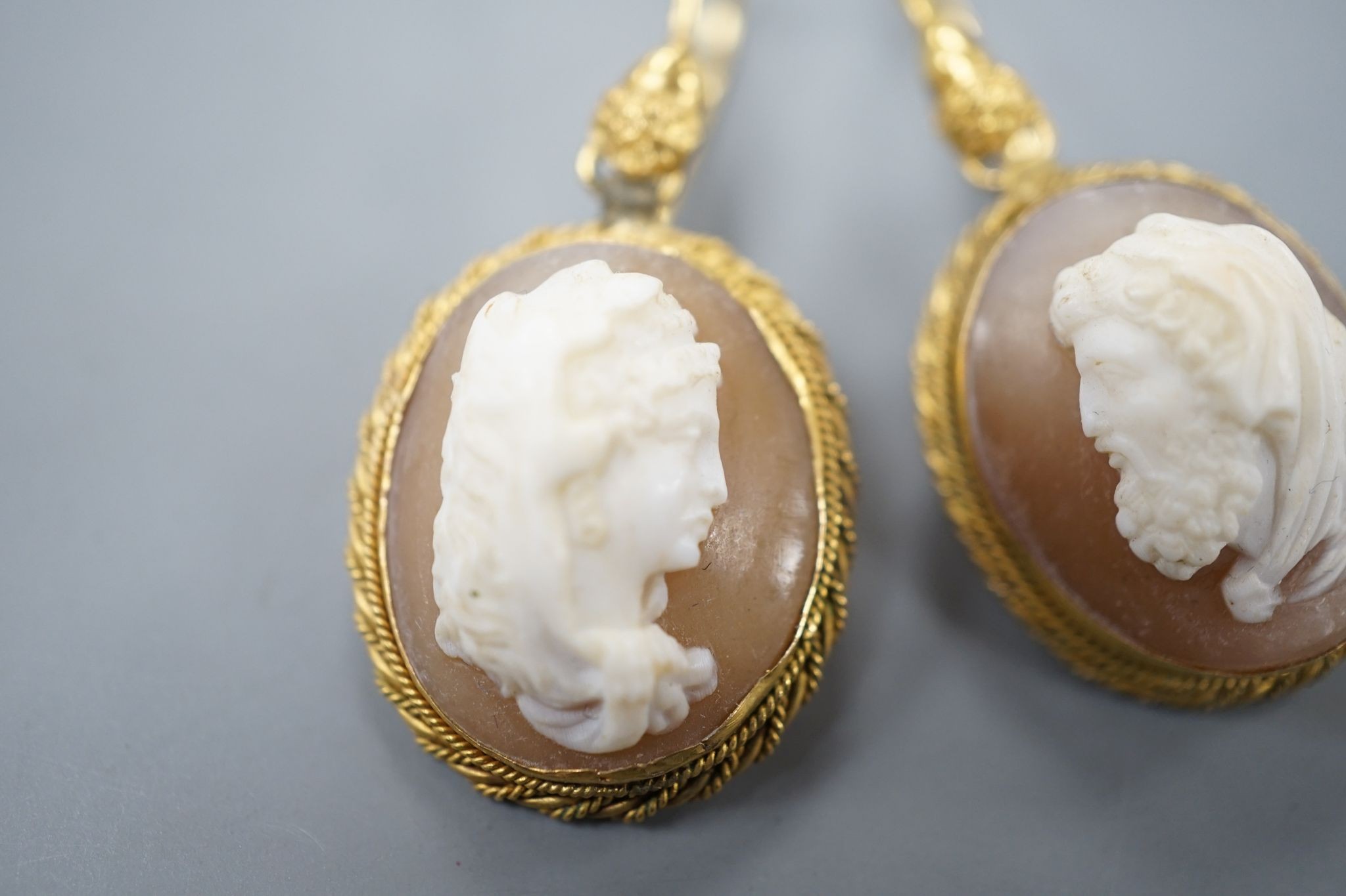 A pair of early 20th century yellow metal and oval cameo shell earrings, carved with a lady to sinister and a gentleman to dexter, overall 40mm, gross 6.2 grams.